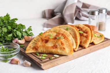 Hafif arka planda lezzetli cheburekler olan ahşap tahta tahta.