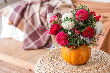 Balkabağı ve güzel çiçekler yatak odasındaki rattan puf, yakın plan.