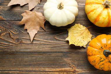 Cadılar Bayramı balkabaklarıyla ve ahşap arka planda sonbahar yapraklarıyla kompozisyon