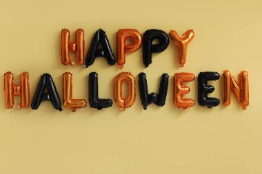 Sarı zemin üzerinde balonlardan yapılmış Mutlu Cadılar Bayramı metni