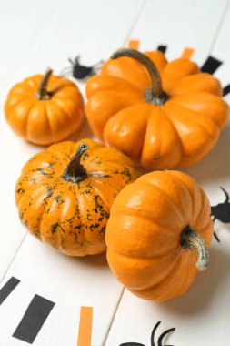 Beyaz ahşap arka planda örümcekleri olan Cadılar Bayramı balkabakları, yakın plan