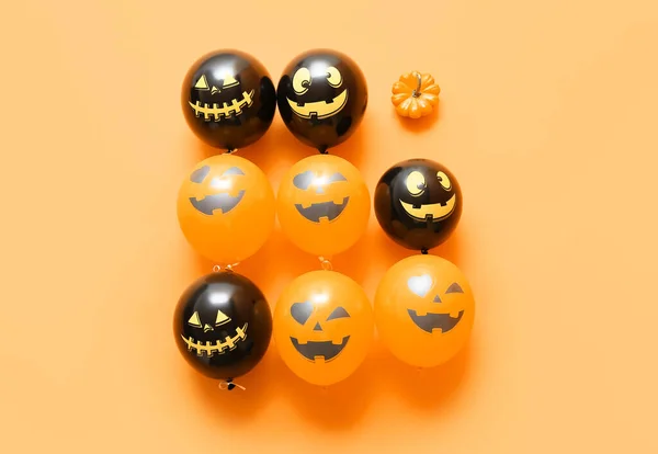 Funny Halloween balloons and pumpkin on color background