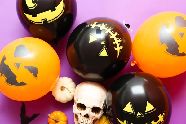 Halloween balloons, scull and pumpkins on color background