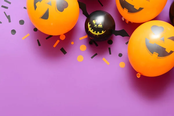 Funny Halloween balloons and confetti on lilac background