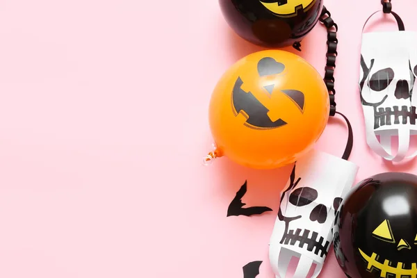 Funny Halloween balloons and paper lanterns on pink background