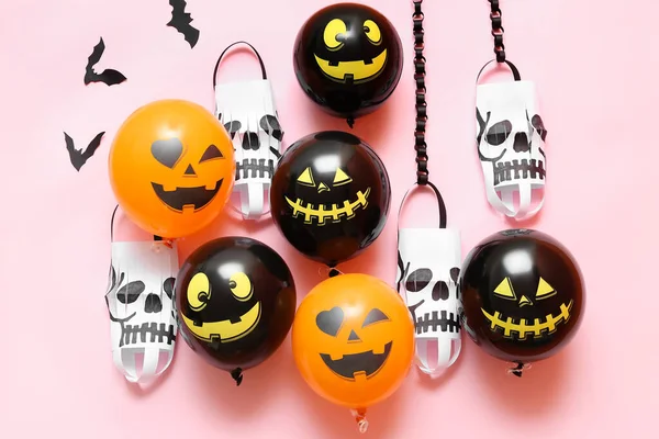 Funny Halloween balloons and paper lanterns on pink background