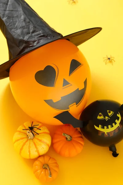 Composition with Halloween balloons and pumpkins on color background, closeup