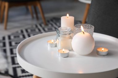 Oturma odasında yanan mumlar olan beyaz masa, yakın plan.