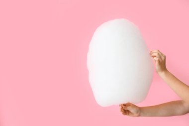 Pembe arka planda pamuk helvası olan kadın elleri