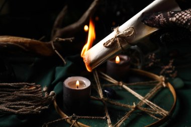 Cadı yanan parşömeni koyu arkaplanda tutuyor, yakın plan