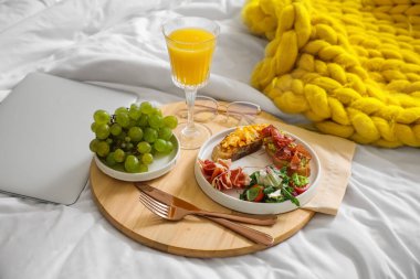 Tahta tepsi, lezzetli kahvaltı ve dizüstü bilgisayar.