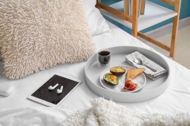 Lezzetli kahvaltı tepsisi, tablet bilgisayar ve kulaklıklar.