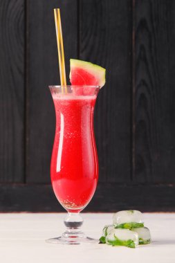 Masanın üzerinde koyu ahşap arka planda duran bir bardak taze karpuz.