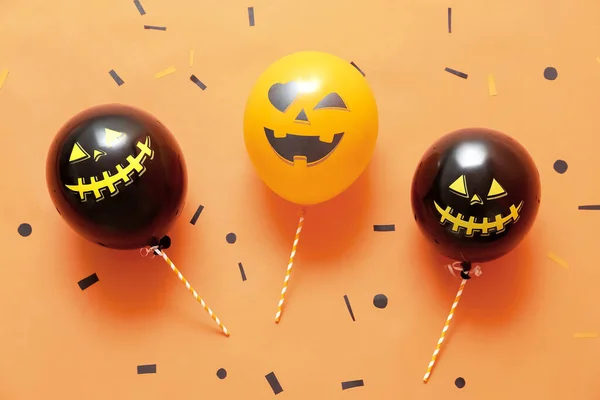 Funny Halloween balloons and confetti on color background