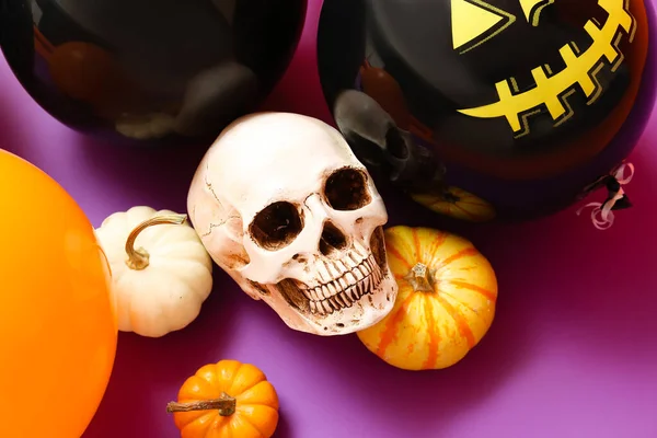Halloween balloons, scull and pumpkins on color background, closeup