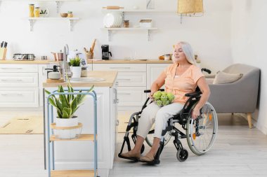 Mutfakta fiziksel engelli olgun bir kadın var.