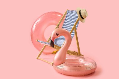 Güverte sandalyesi ve plaj aksesuarları pembe arka planda.