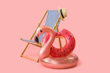 Güverte sandalyesi ve plaj aksesuarları pembe arka planda.