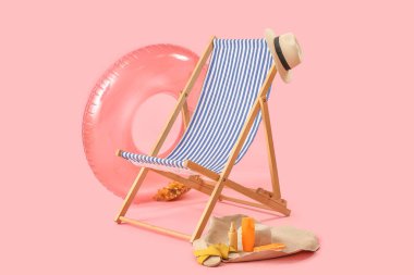 Güverte sandalyesi ve plaj aksesuarları pembe arka planda.