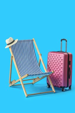 Plaj sandalyesi ve açık mavi arka planda bavul.