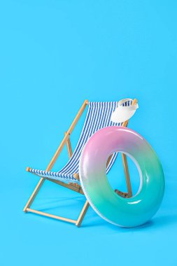 Güverte sandalyesi ve açık mavi zemin üzerinde şişirilebilir halka