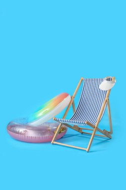 Güverte sandalyesi ve açık mavi zemin üzerinde şişirilebilir halkalar