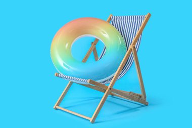 Güverte sandalyesi ve açık mavi zemin üzerinde şişirilebilir halka