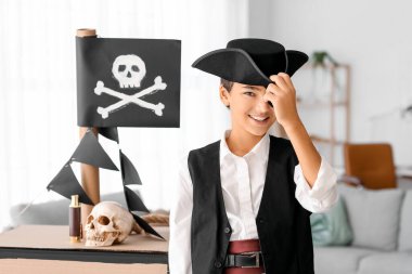 Evde karton gemiyle korsan gibi giyinmiş küçük çocuk.