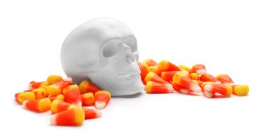 Cadılar Bayramı şekerleri ve beyaz arka planda insan kafatası