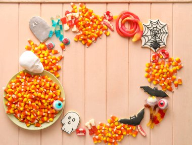 Bej ahşap arka planda Cadılar Bayramı jölesi ve kurabiyelerinden yapılmış çerçeve