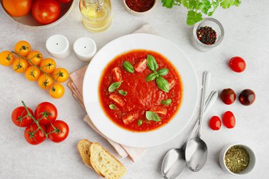 Lezzetli bir tabak domates çorbası ve hafif arka planda malzemelerle kompozisyon.