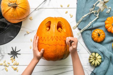 Beyaz ahşap arka plana balkabağı oyan kadın.