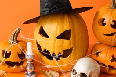 Balkabağı, mum ve kafatası turuncu arka planda.