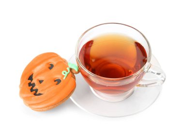 Cadılar Bayramı balkabağı kurabiyesi ve beyaz arka planda bir fincan çay.