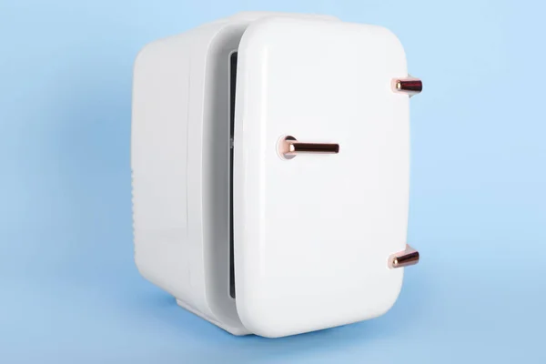 Small cosmetic refrigerator on blue background