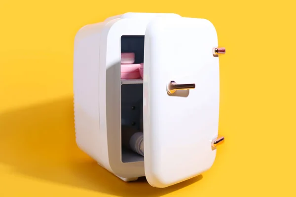 Small cosmetic refrigerator on yellow background