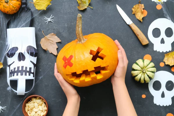 Balkabağı Jack-O-Lantern balkabağı ve arka planda düşmüş yaprakları olan kadın.