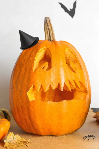 Jack-O-Lantern pumpkin on table near white wall