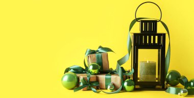 Sarı zemin üzerinde mum, toplar ve hediyeler olan güzel Noel feneri