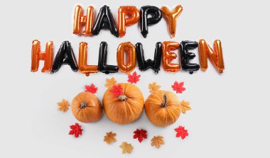 Balonlardan, kabaklardan ve beyaz arkaplanda sonbahar yapraklarından oluşan Cadılar Bayramınız kutlu olsun.