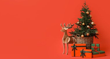 Tahta rengeyiği ve Noel ağacı ve kırmızı arka planda hediyeler.