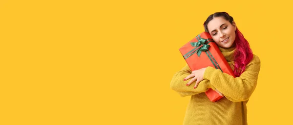 美しい女性を保持クリスマスギフトボックス上の黄色の背景とともにスペースのためのテキスト — ストック写真