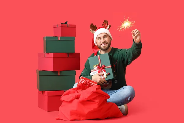 Ευτυχισμένος Άνθρωπος Δώρα Χριστουγέννων Sparkler Και Τσάντα Σάντα Κόκκινο Φόντο — Φωτογραφία Αρχείου