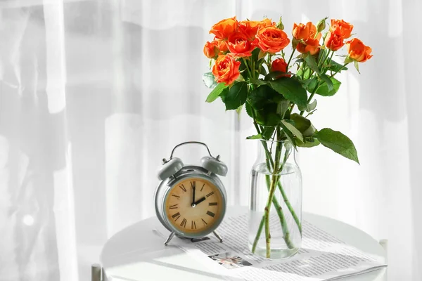 美しいバラの花束と目覚まし時計付き花瓶部屋のテーブル — ストック写真