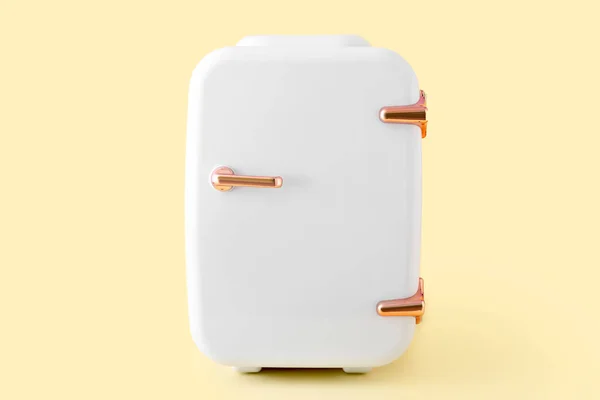 Small cosmetic refrigerator on color background