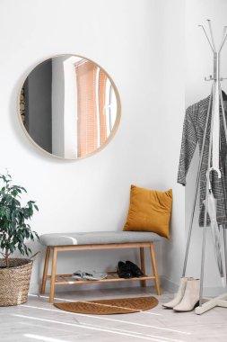 Yuvarlak ayna, bank ve raflı şık bir salon.