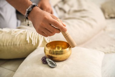 Tibet şarkı kasesi olan genç adam evde, yakın plan.