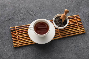 Bir fincan sıcak siyah çay ve koyu arkaplanda kuru yapraklar.