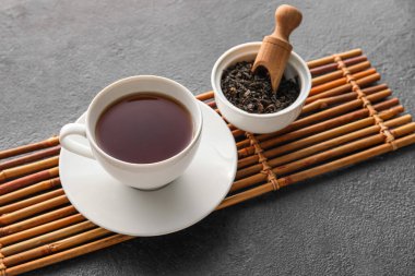 Bir fincan sıcak siyah çay ve koyu arkaplanda kurumuş yapraklar, yakın plan.