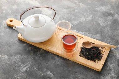 Siyah çay, çaydanlık ve koyu arkaplanda kurumuş yapraklı ahşap tahta.